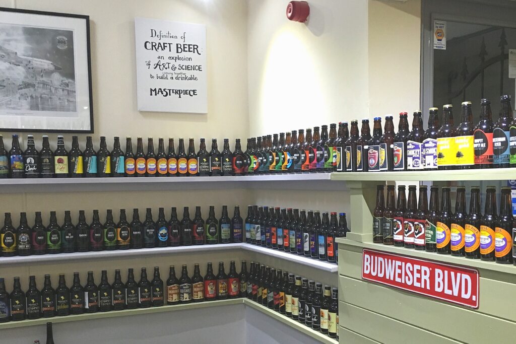 Shelves of beer bottles. A red Budweiser Boulevard street sign. A on the wall that reads "Definition of CRAFT BEER: An explosion OF ART & SCIENCE to build a drinkable MASTERPIECE".