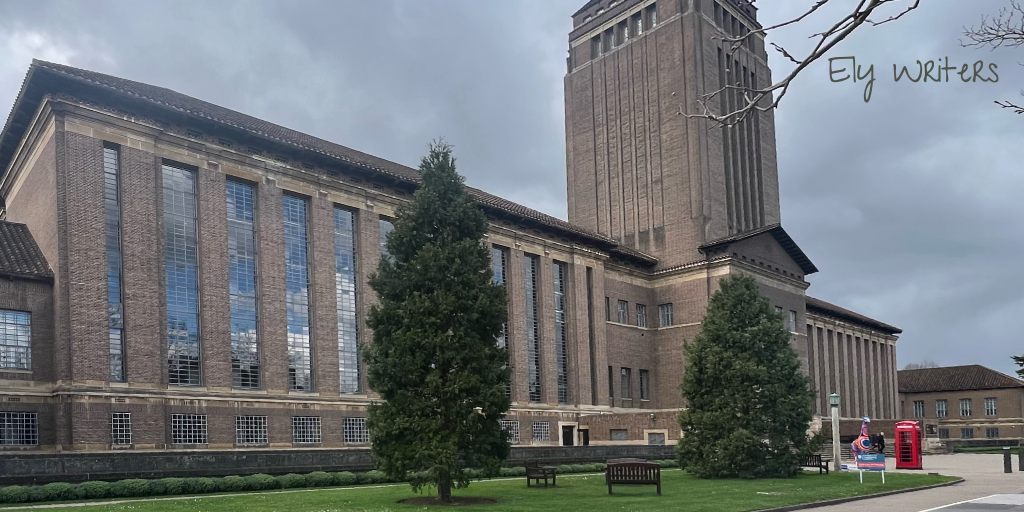 The front façade of the Cambridge University Library (the UL). It's a wide, brown-brick building with a central tower. The building has tall windows spanning multiple floors. 'Ely Writers' is overlaid in the top right corner.