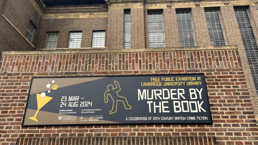 A sign hanging on the front wall of the Cambridge University Library. The sign has a stylised outline of a dead body as seen in on-screen crime fiction. The sign shows the details of the Murder by the Book exhibition:
23 March – 24 August;
Free public exhibition at the Cambridge University Library